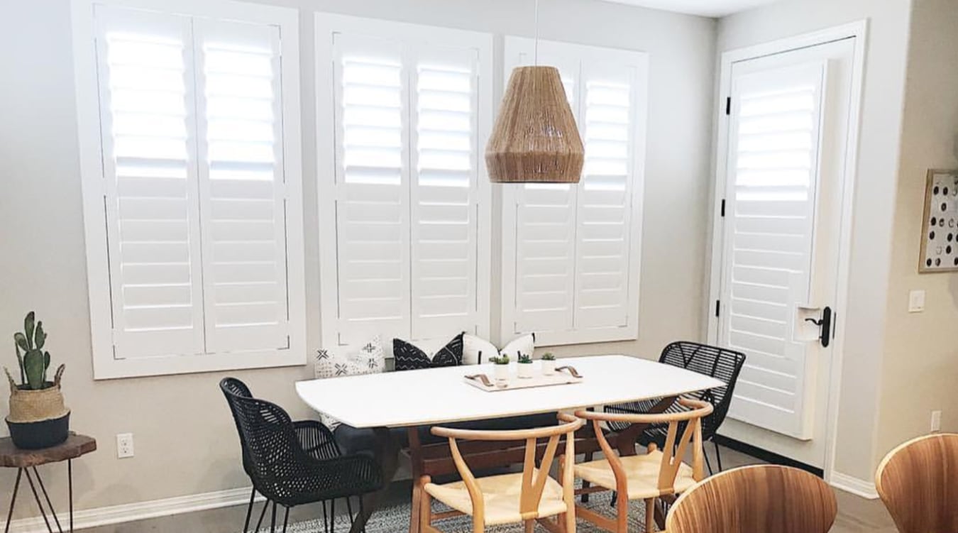 Bring harmony to windows of different sizes by using the same custom window treatments on all of them. Polywood® shutters in a dining room.